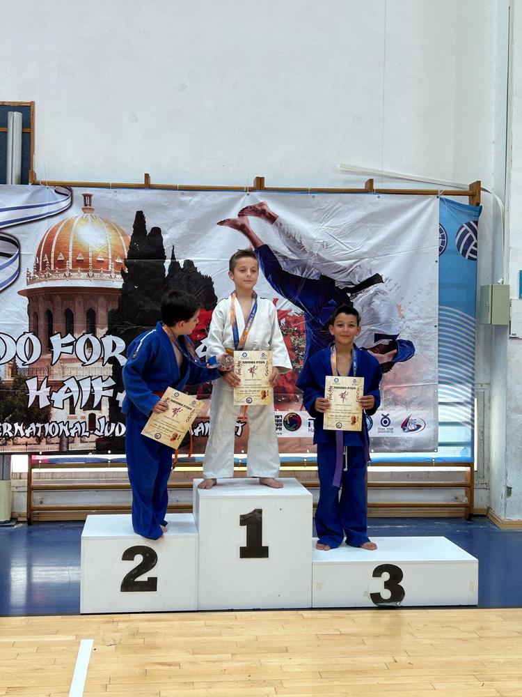 שלושה ילדים עם תעודות על הפודיום בטורניר Judo for Peace בחיפה
